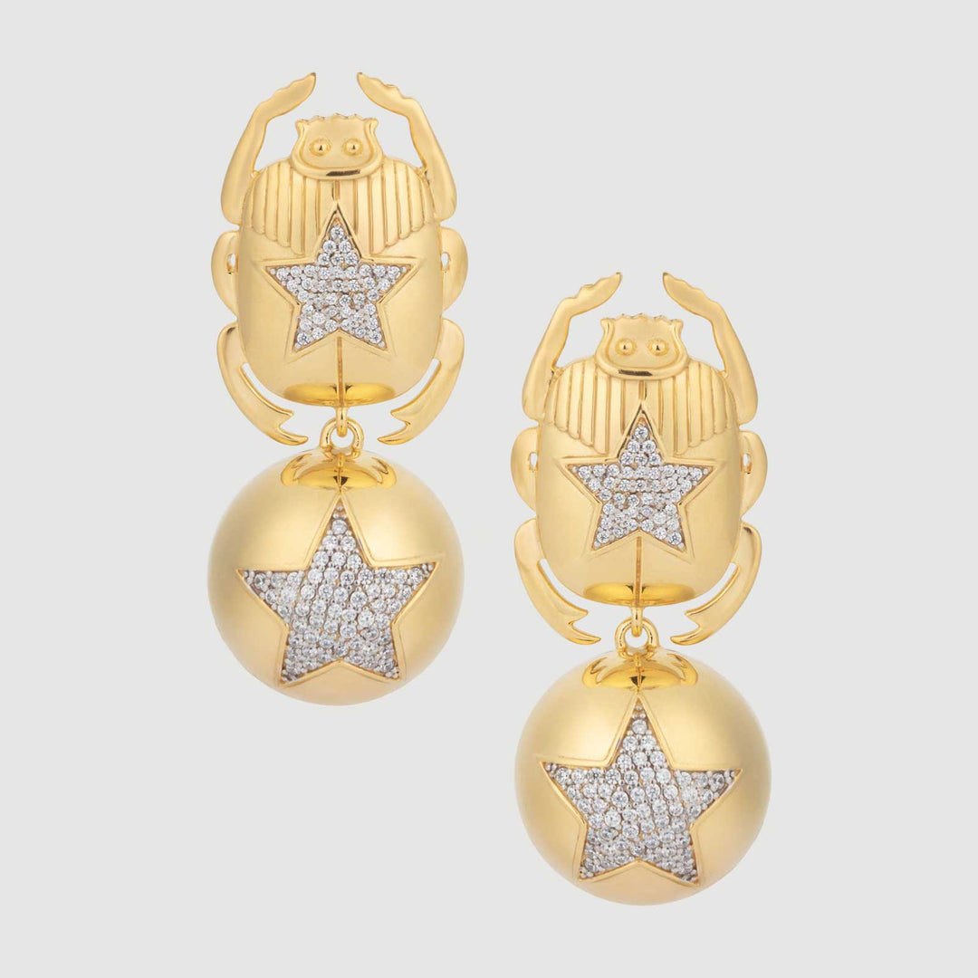 Gold scarab earrings with star designs on a light gray background